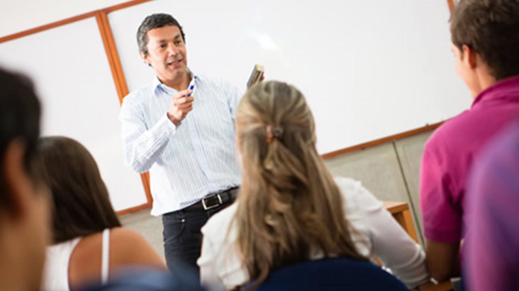 Profesor dando clases. Los estudiantes están de mirando hacia el frente